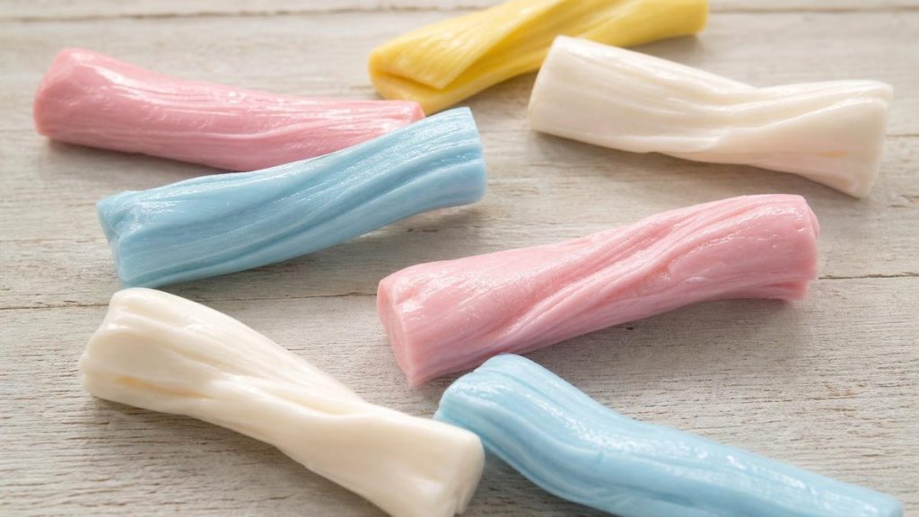 Unwrapped pastel taffy candy bars in pink, blue and yellow on a wooden table